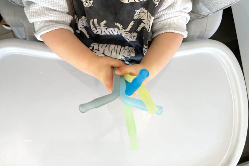 Small child holding colorful straws used to drink meat stock.